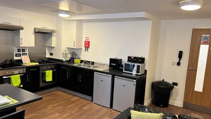 Una cocina moderna con electrodomésticos de acero inoxidable, encimera negra y suelo de madera.