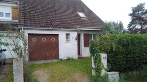 Une maison de plain-pied avec une porte marron, une petite fenêtre et une boîte aux lettres.