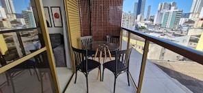 Un balcón con una mesa y sillas, un muro con azulejos y vistas a la ciudad.