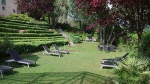 Un jardin aménagé avec des terrasses enjambées de pelouses, des espaces de détente en plein air et un escalier menant à un niveau supérieur.