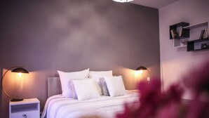 Une chambre à coucher avec un lit, deux tables de chevet et des étagères fixées au mur.