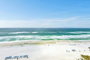 Ein Strand mit Reihen blauer Liegestühle und einem Sandufer.