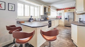 Una cocina moderna con una isla central, taburetes de bar, un refrigerador y un microondas.