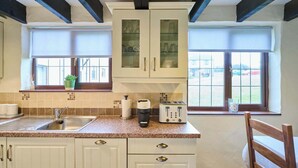 A kitchen with a granite countertop, a sink, a toaster, and a window with a view of the outside. - Host & Stay | Providence Cottage (Woolacombe)