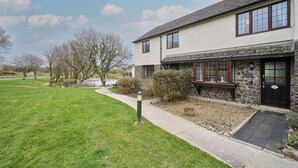 A two-story building with a stone facade, a small porch, and a paved pathway leading to the entrance. - Host & Stay | Providence Cottage (Woolacombe)