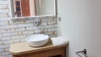 A bathroom with a white sink, wooden vanity, and a large mirror.