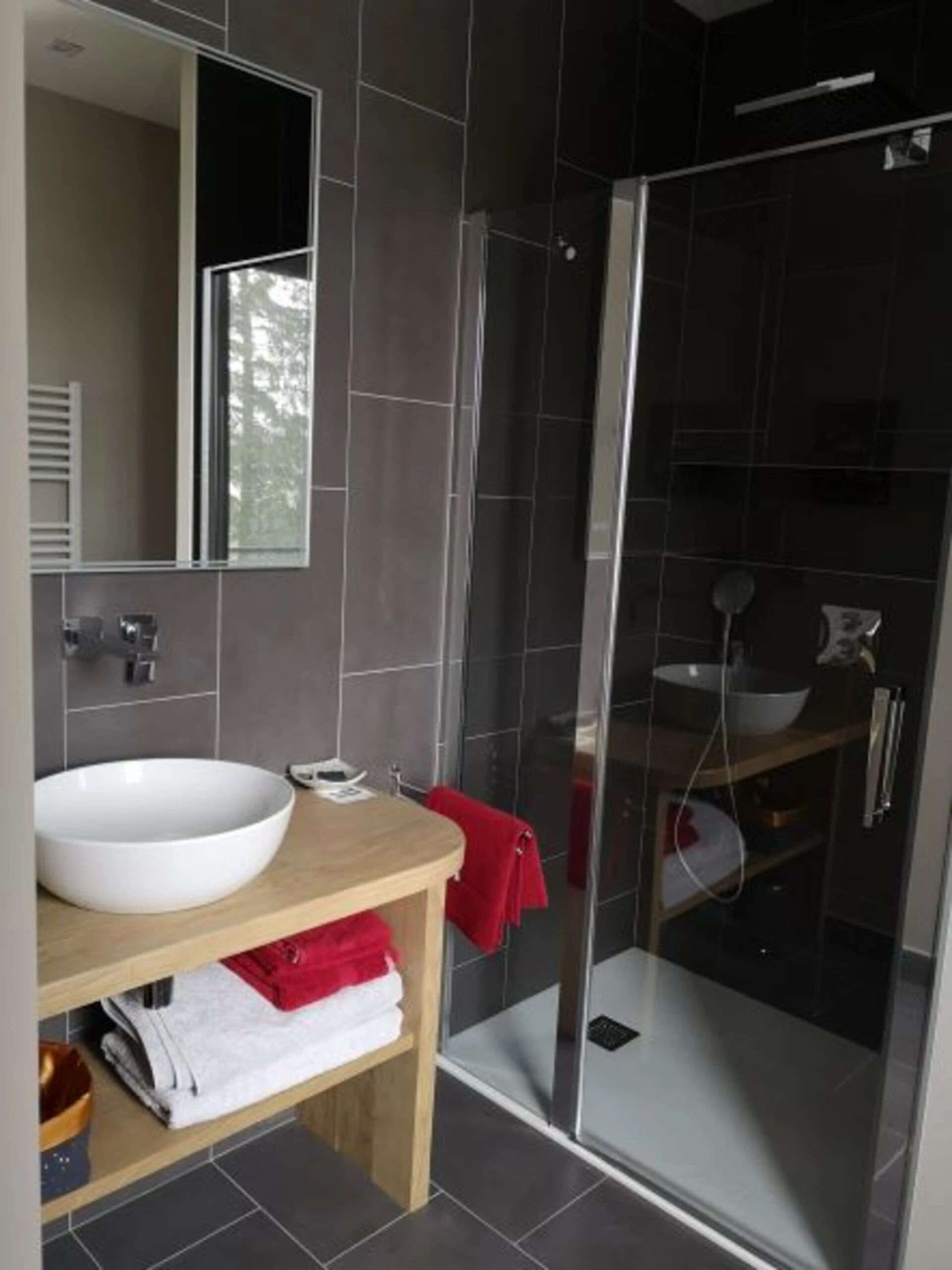 A modern bathroom with a large white sink, a mirror, and a glass-enclosed shower.