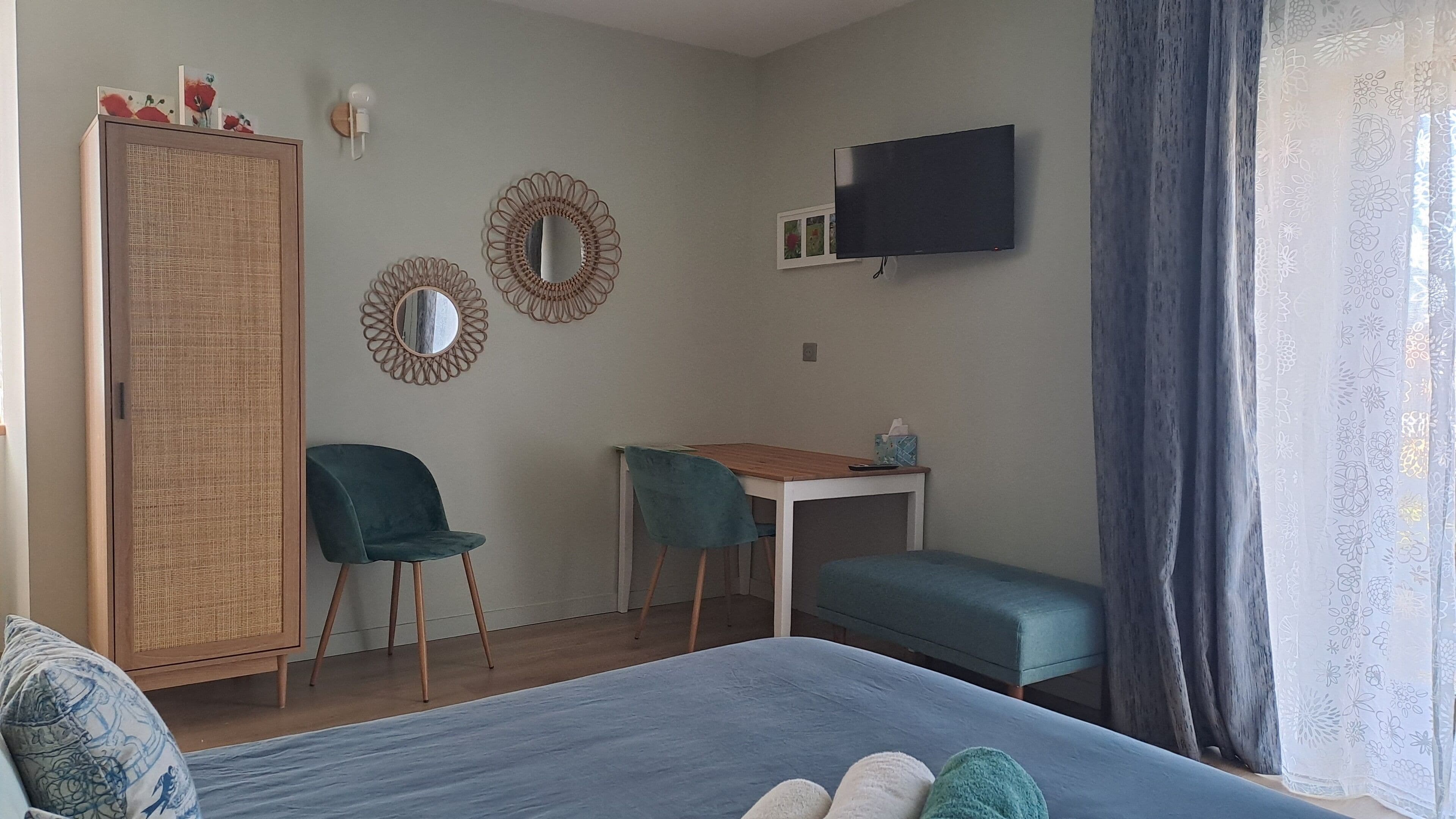 Una camera da letto con un letto, una scrivania, due sedie, un armadio e una televisione.