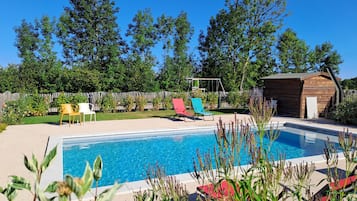 Una piscina al aire libre de temporada, sillones reclinables de piscina