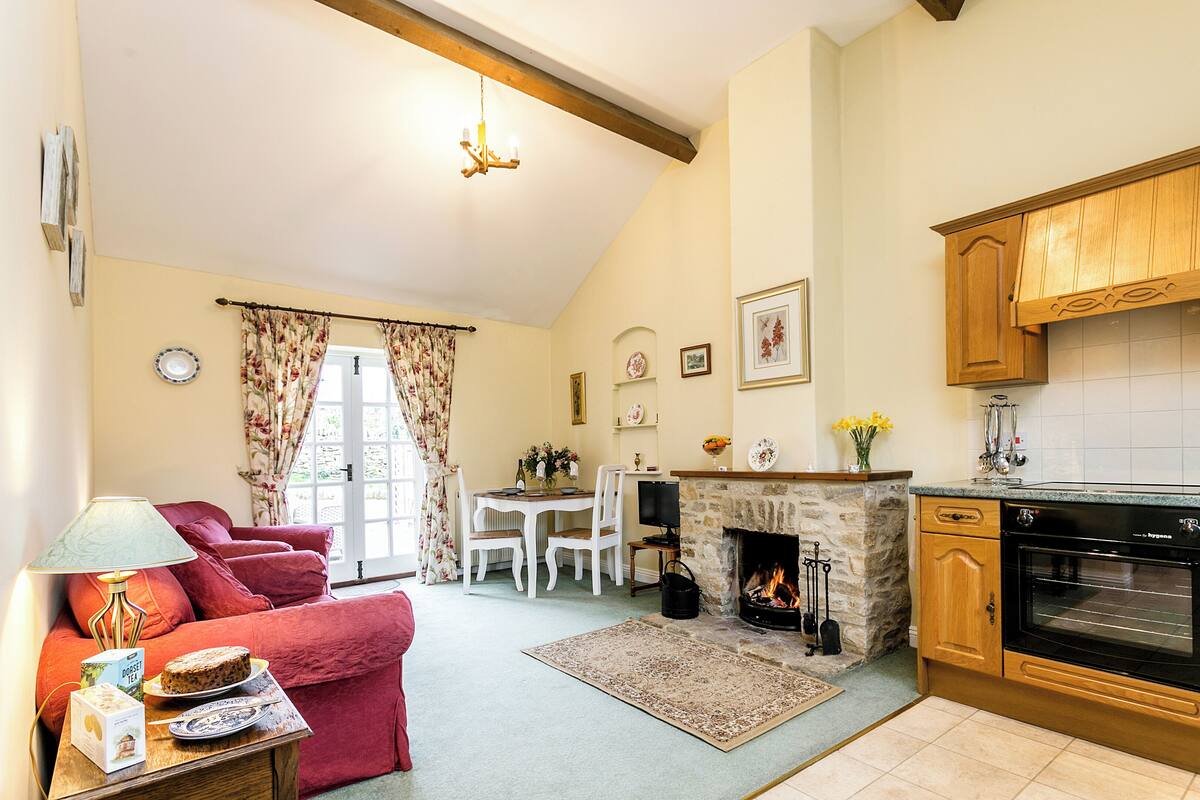 A cozy living room with a fireplace, a dining area, and a kitchen with wooden cabinets.