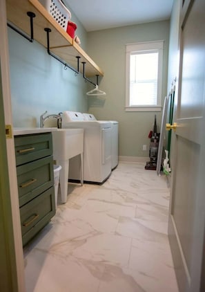 A laundry room with a washing machine, dryer, and shelves above the sink.