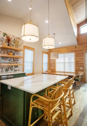 Una cocina moderna con una isla grande, detalles de madera e iluminación colgante.
