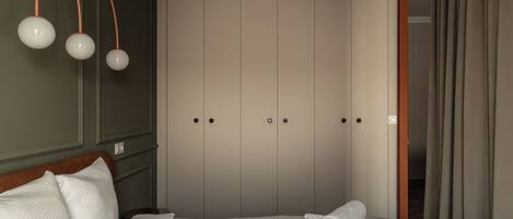 Un lit bien fait, avec des serviettes pliées, une tête de lit en bois et une armoire à deux portes.