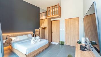 A modern hotel room with a wooden bed, a desk with a computer, and a balcony.
