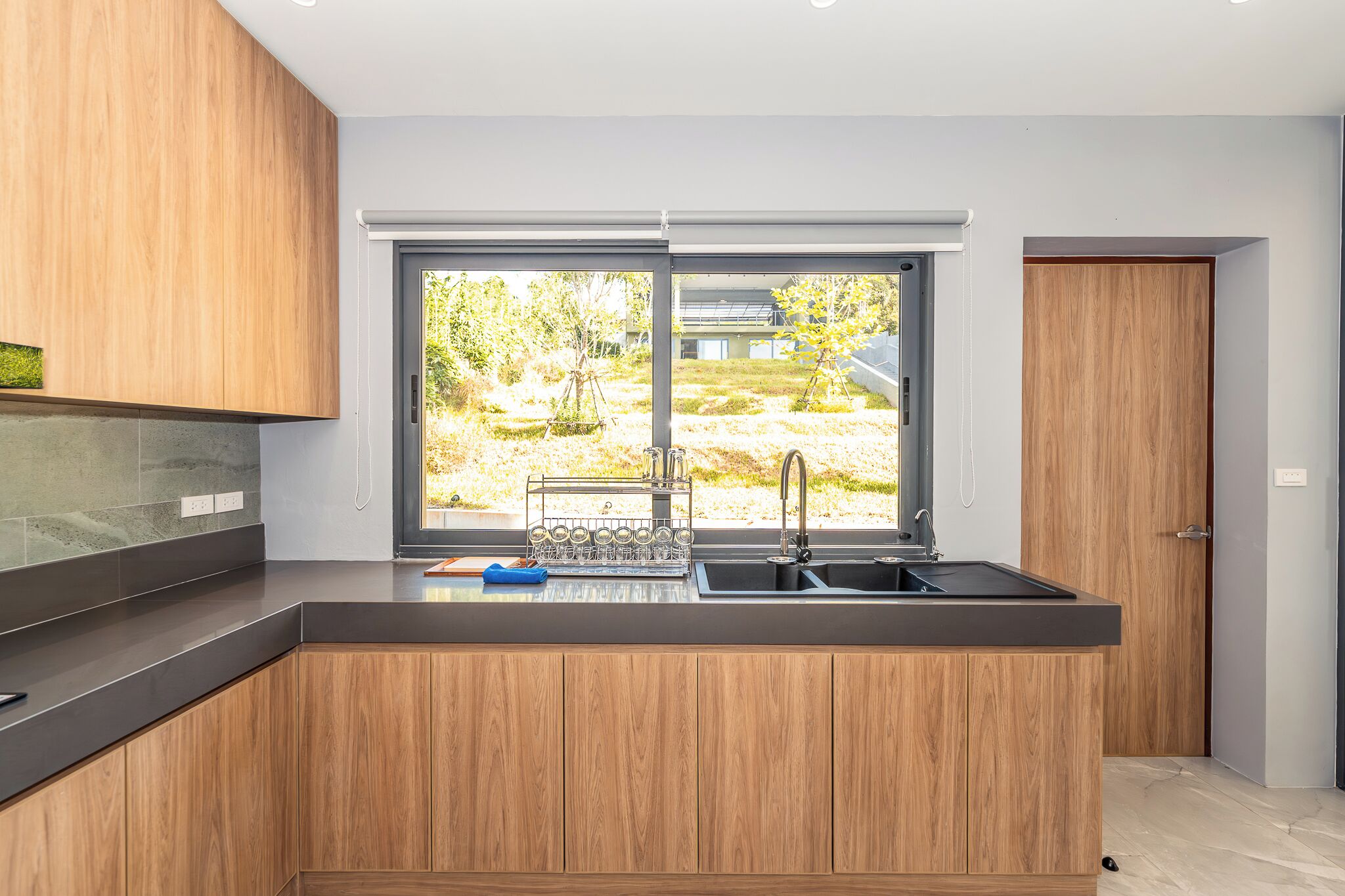 Una cocina moderna con un amplio ventanal, armarios de madera y un lavamanos integrado.