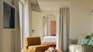 A modern hotel room with a sofa, armchair, and a round coffee table. - Edgar Suites - Église (Paris)