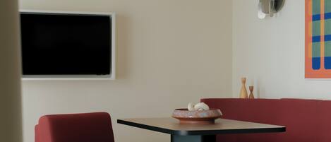 Un salon moderne avec un canapé rouge, une table noire et un téléviseur à écran plat fixé au mur.