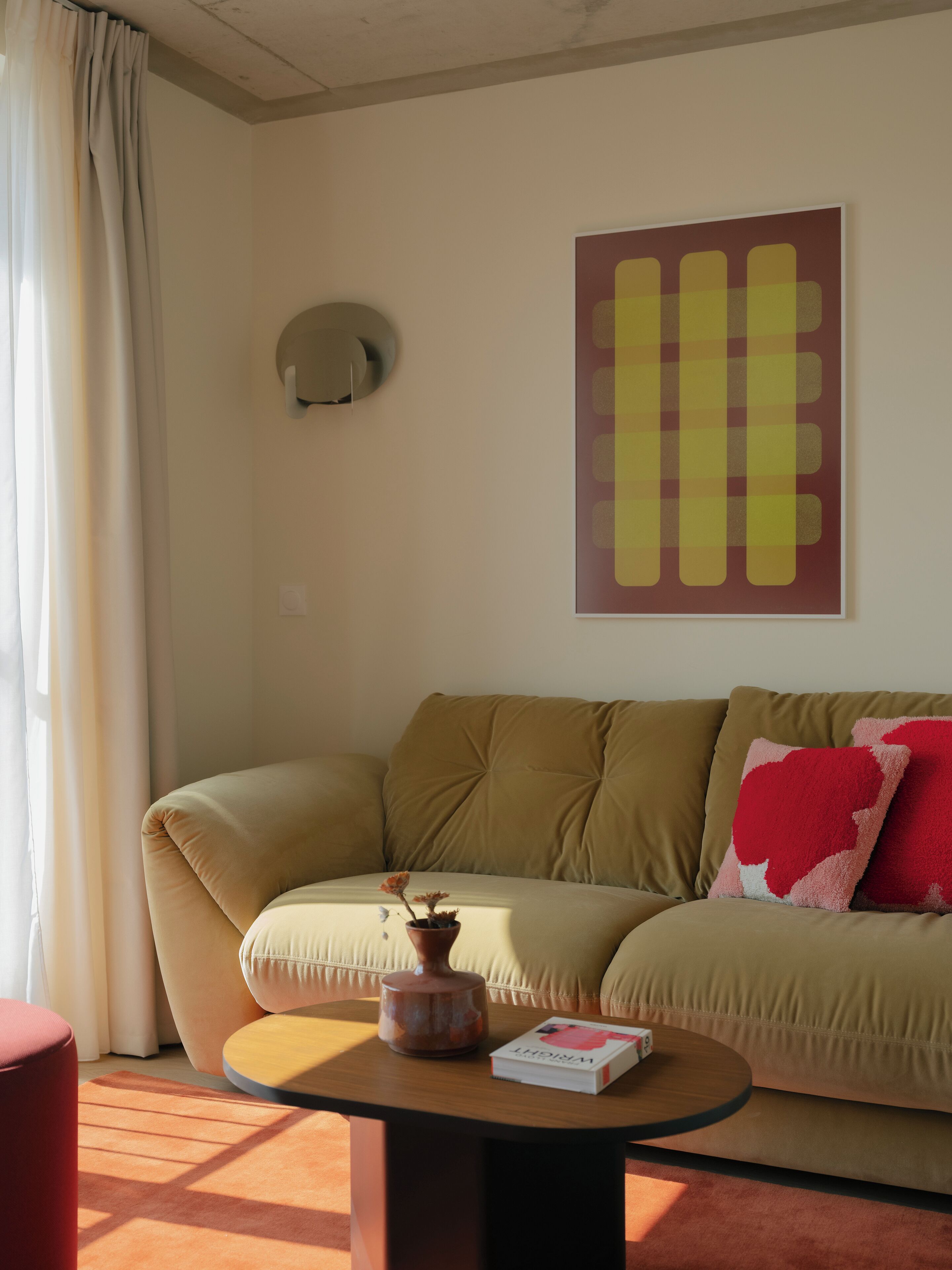 Een woonkamer met een beige bank, een ronde salontafel, een potplant en een boek.