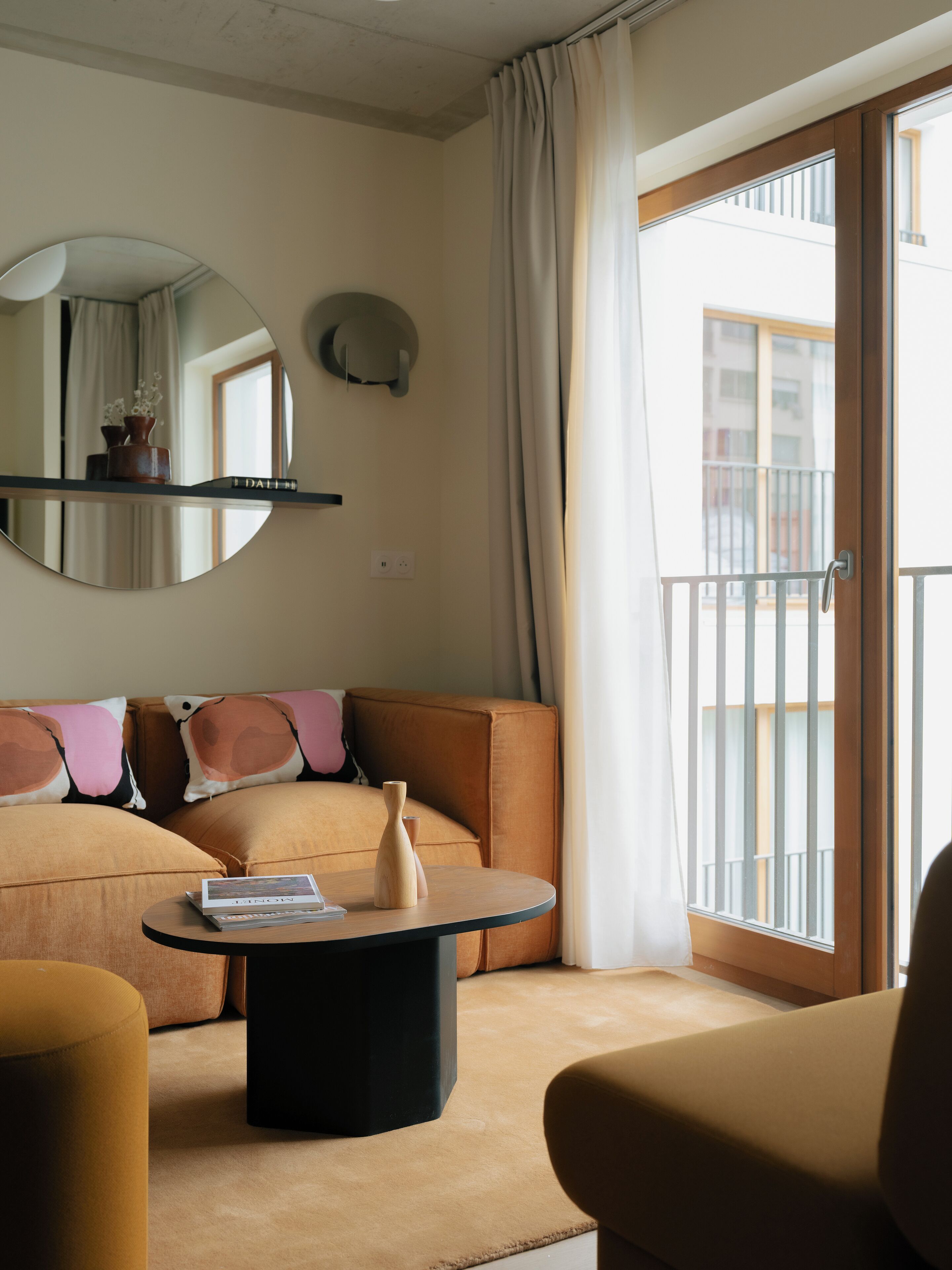Un salon moderne avec un canapé, une table basse ronde et un grand miroir.