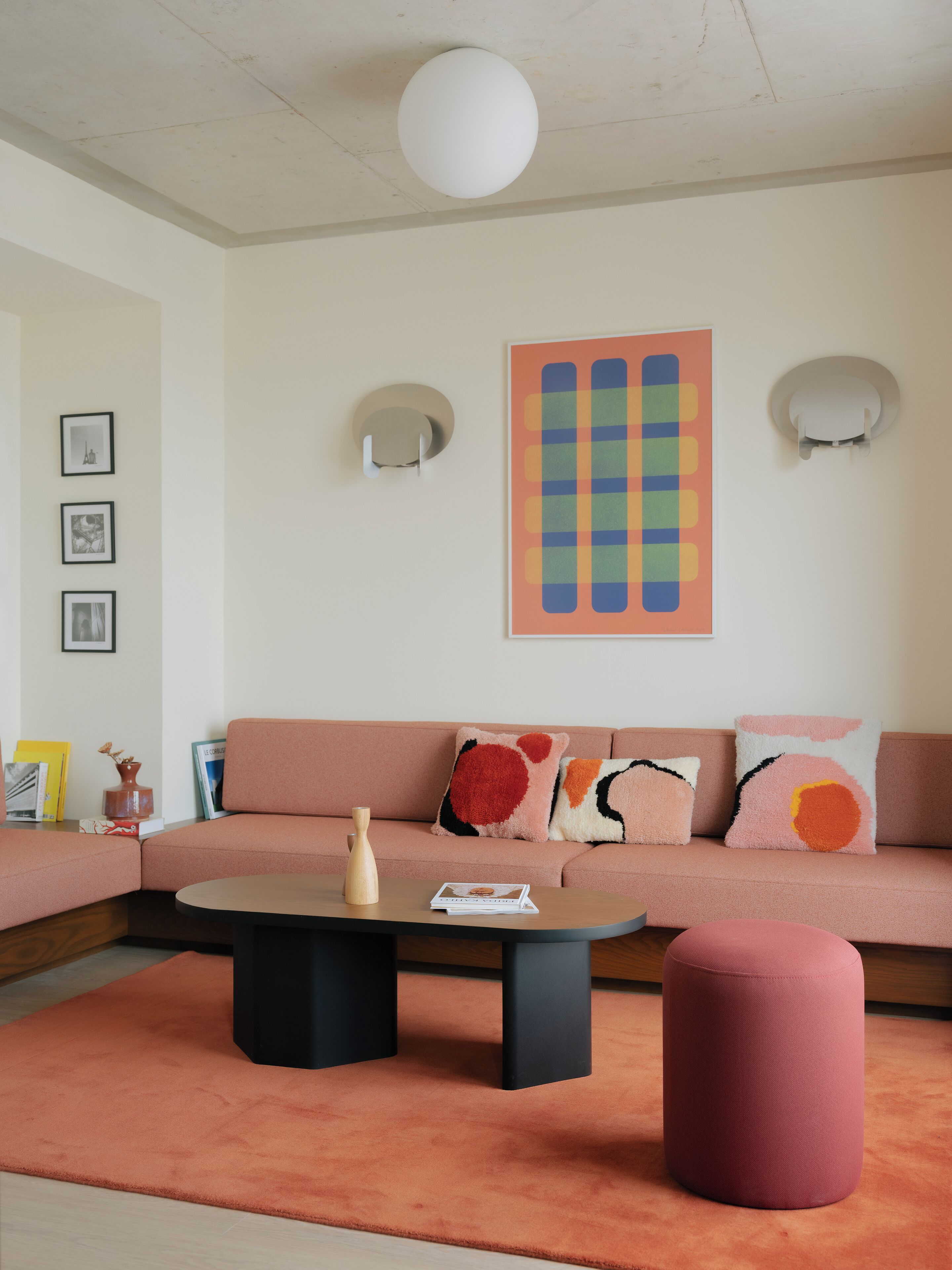 Een moderne woonkamer met een bank, een poef, een salontafel en wanddecoratie.