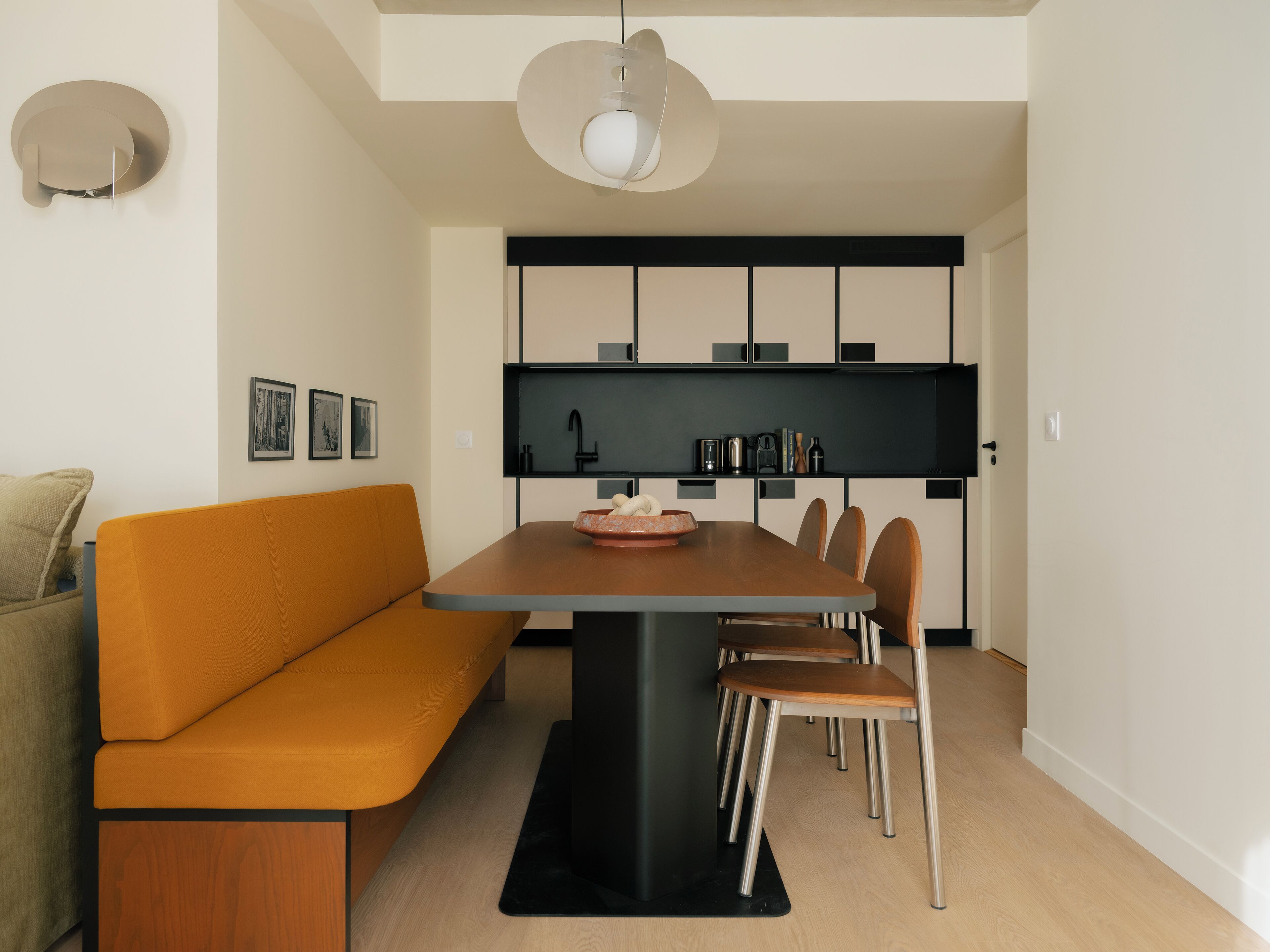 A modern kitchen with a central island, a dining table with chairs, and a sofa.