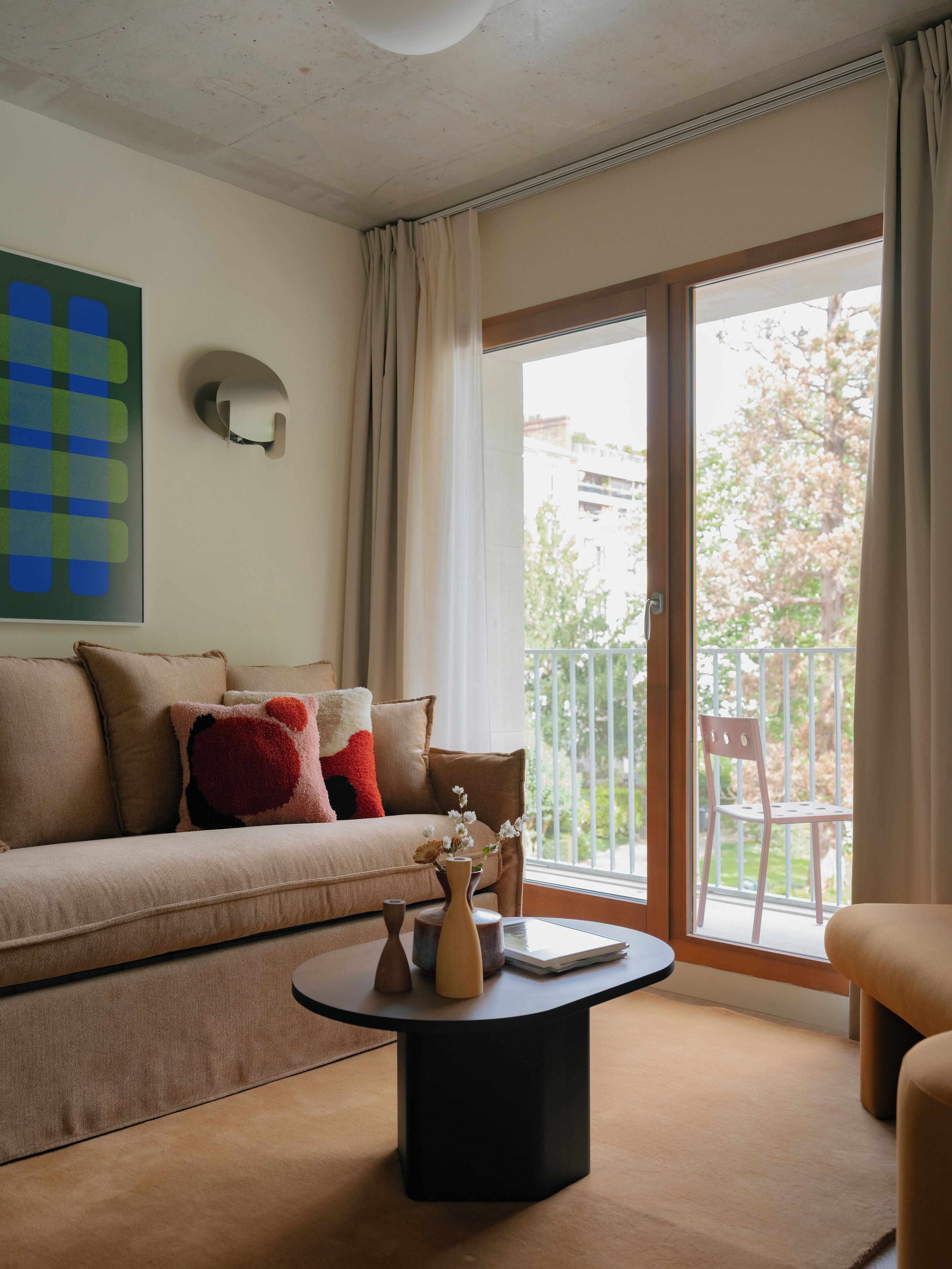 A living room with a sofa, a coffee table, and a view of the outside.