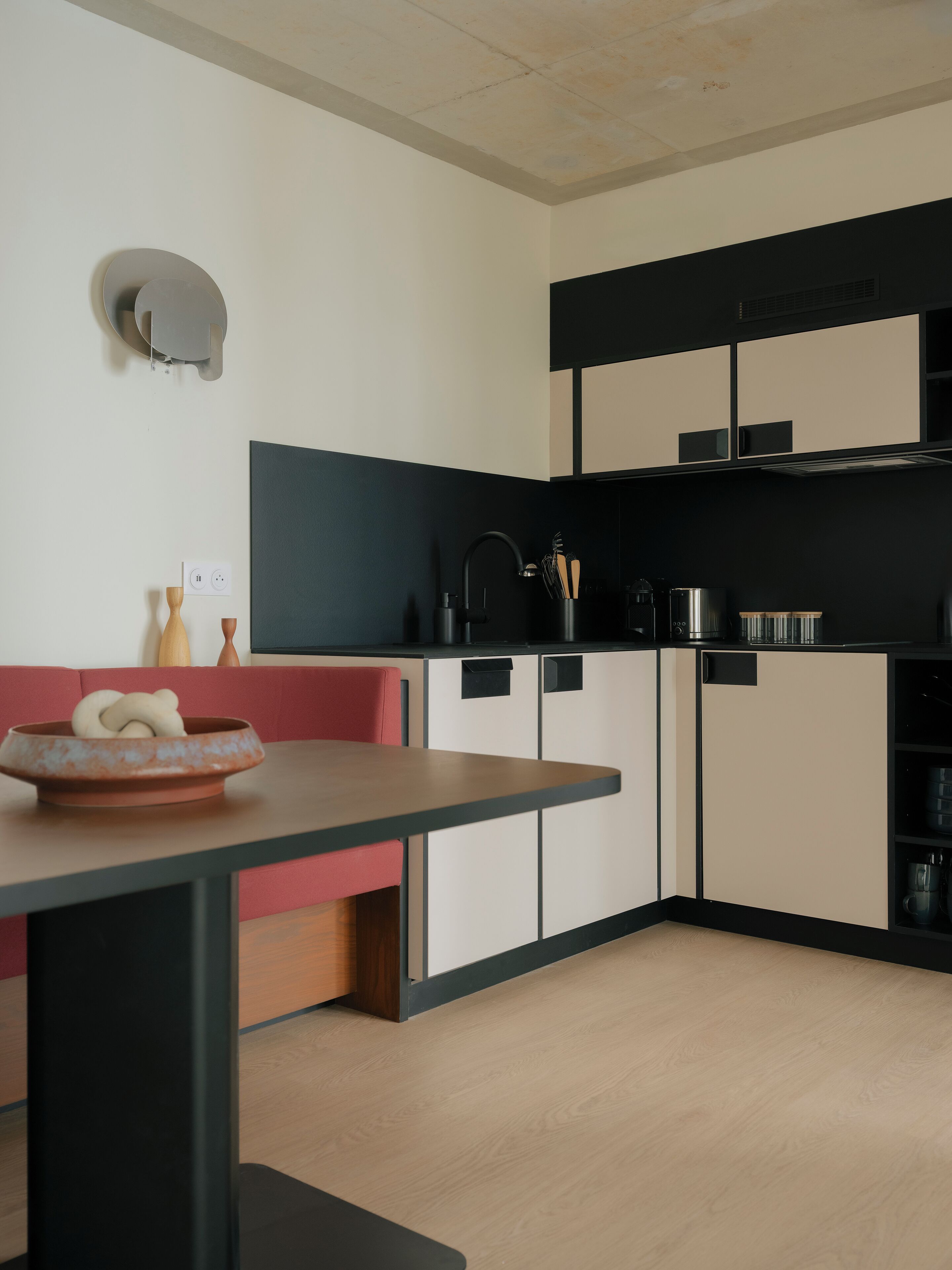 Une cuisine moderne avec une table à manger en bois, un four encastré et un plan de travail noir.