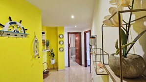 A hallway with a yellow wall, a ship's wheel decoration, and a potted plant. - SeaView Boiro Apartment 2 Bed (Boiro)