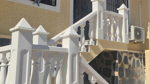 Een gebouw met een beige gevel, witte trapleuning en een stenen trap.