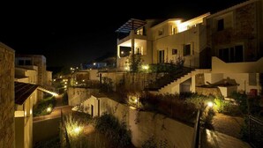 A modern building with a prominent staircase and multiple balconies, surrounded by lush greenery. - EA WHITE VIBES (Baja Sardinia)