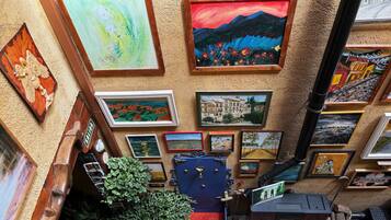 A gallery of framed artworks on a textured wall, a wooden door with a brass handle, and a small green plant.