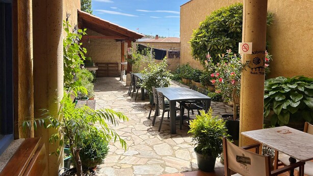 Ein Patio im Freien mit Steinböden, Holzmöbeln und Kübelpflanzen.