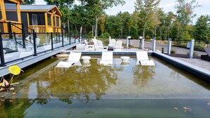 A pool area with lounge chairs and a wooden building in the background. - FINCH - RESORT WITH 12 PROPERTIES.  NATURAL POND FOR SWIMMING. (SEBAGO)