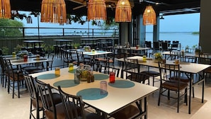Un restaurant avec des tables et des chaises, des lampes en osier suspendues et une vue sur la mer.