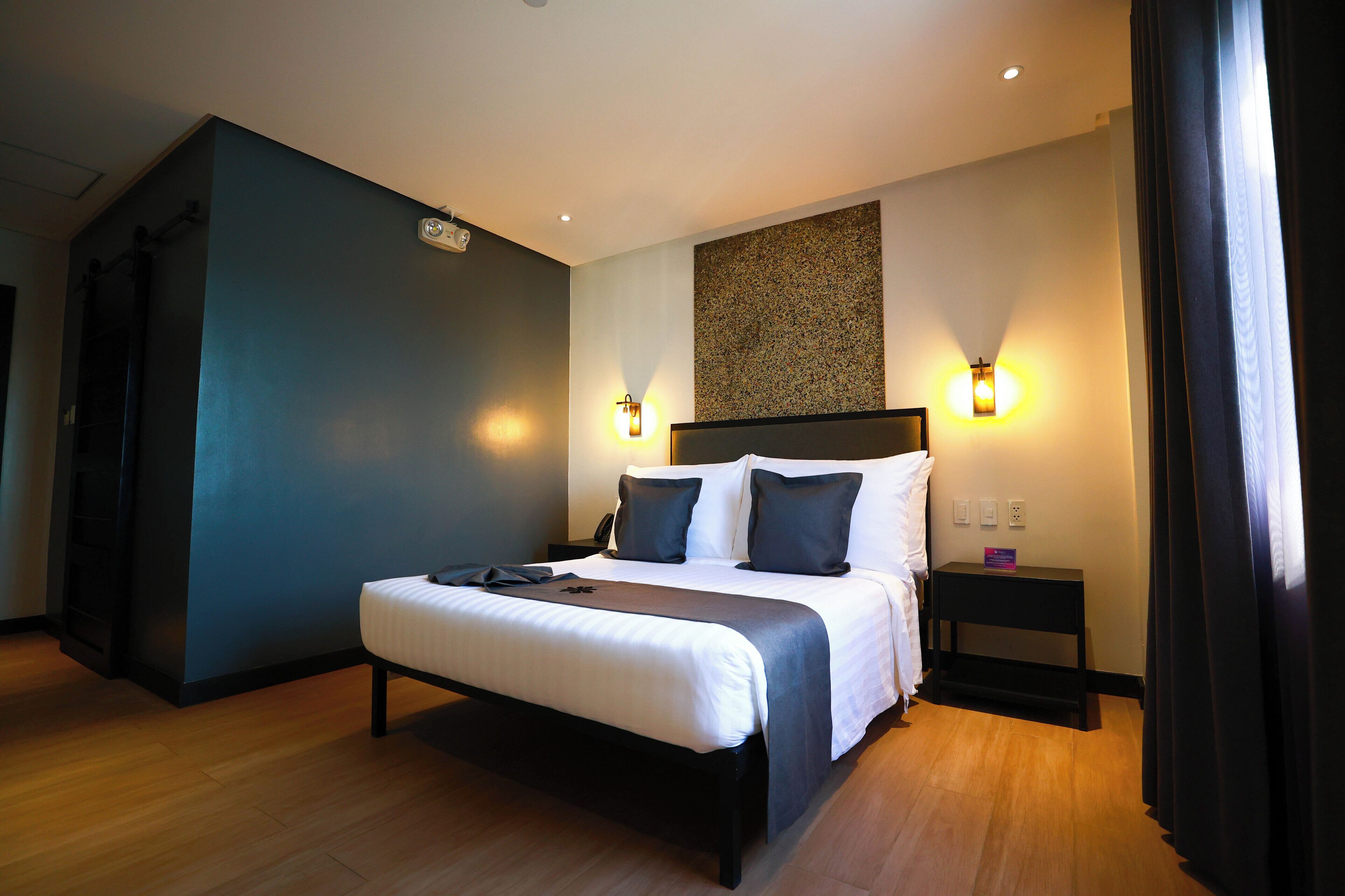 Una habitación de hotel moderna con una cama grande, mesitas de noche e iluminación empotrada.