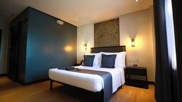 Una habitación de hotel moderna con una cama grande, mesitas de noche e iluminación empotrada.