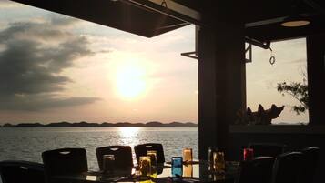 A table set for dining with a view of the sunset over the water.