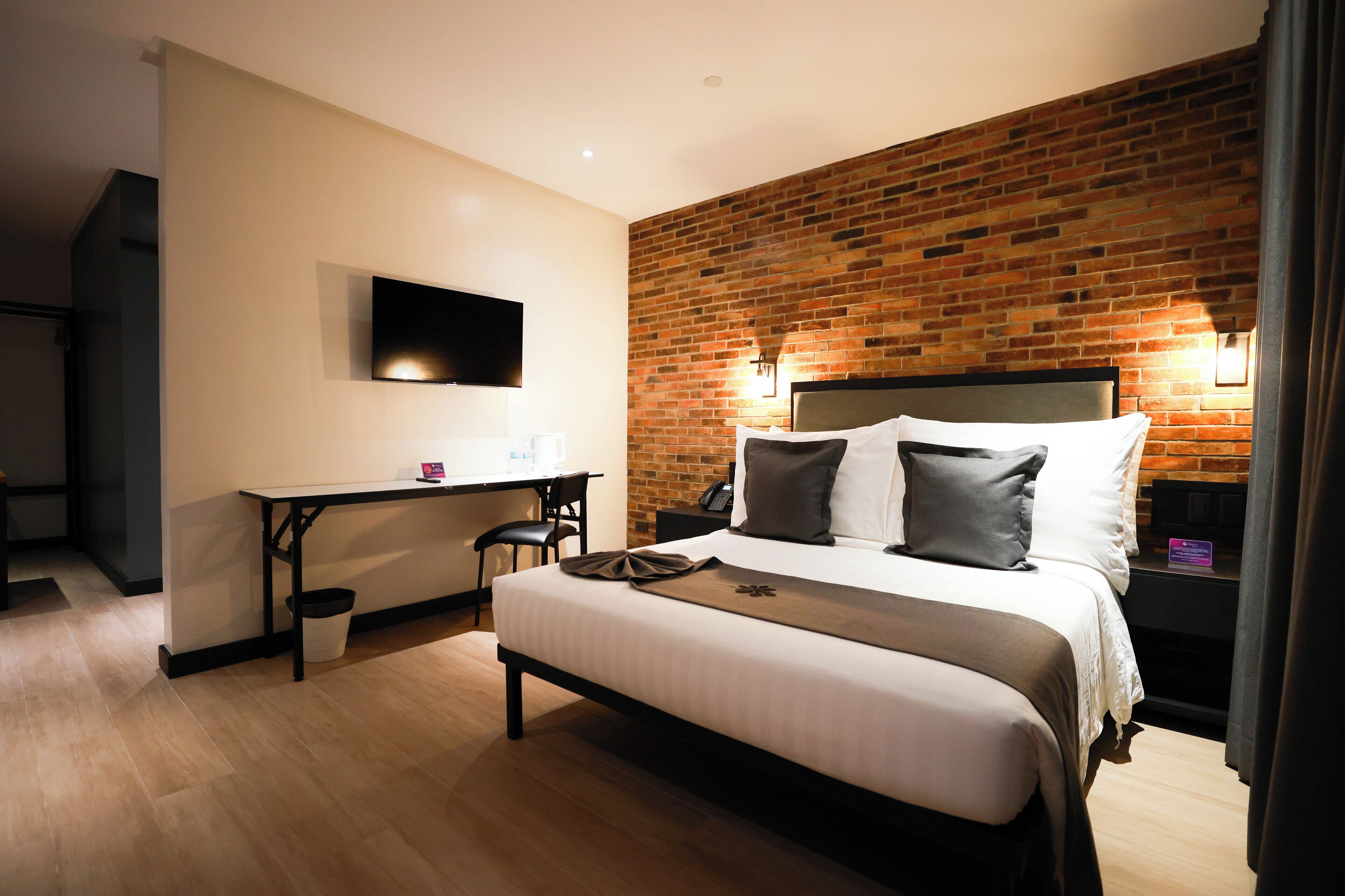 Une chambre d’hôtel avec un grand lit, un bureau et un téléviseur fixé au mur.