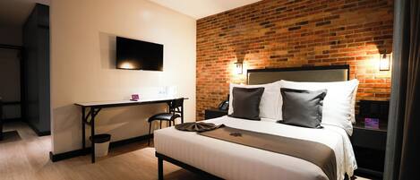 Une chambre d’hôtel avec un grand lit, un bureau et un téléviseur fixé au mur.