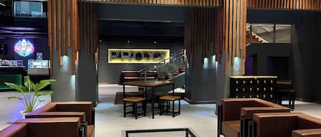 Un hall d’entrée moderne avec des panneaux de bois, un escalier et des espaces aménagés pour s’asseoir.