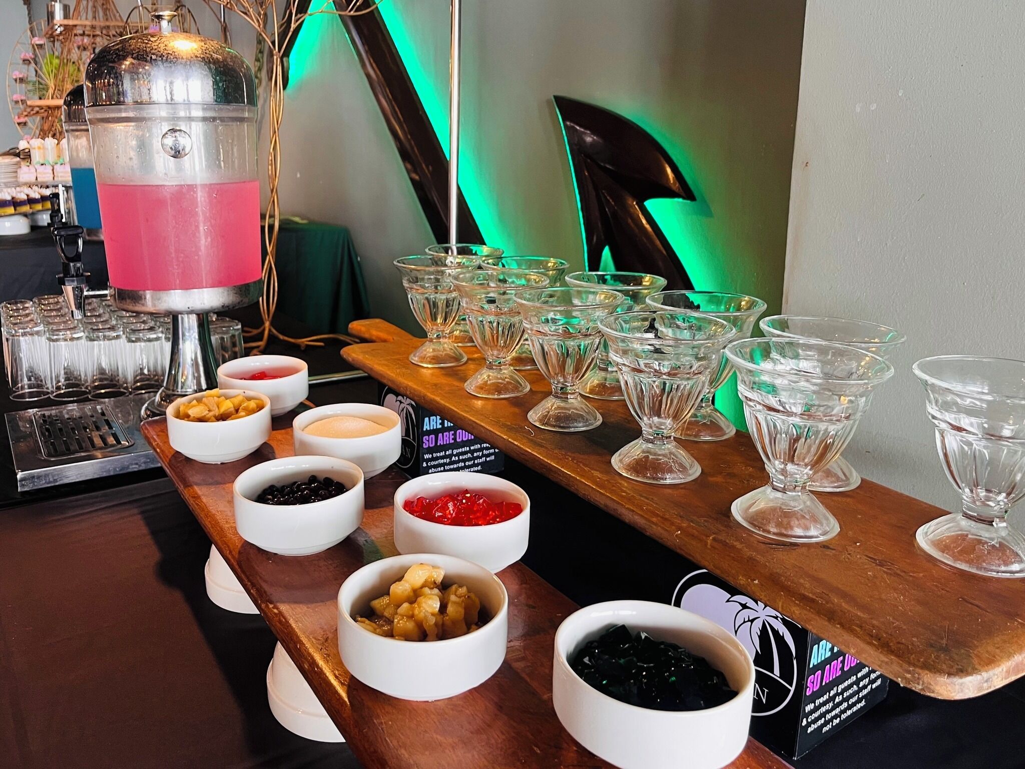 A bar area with a drink dispenser, multiple glasses, and bowls of various food items.