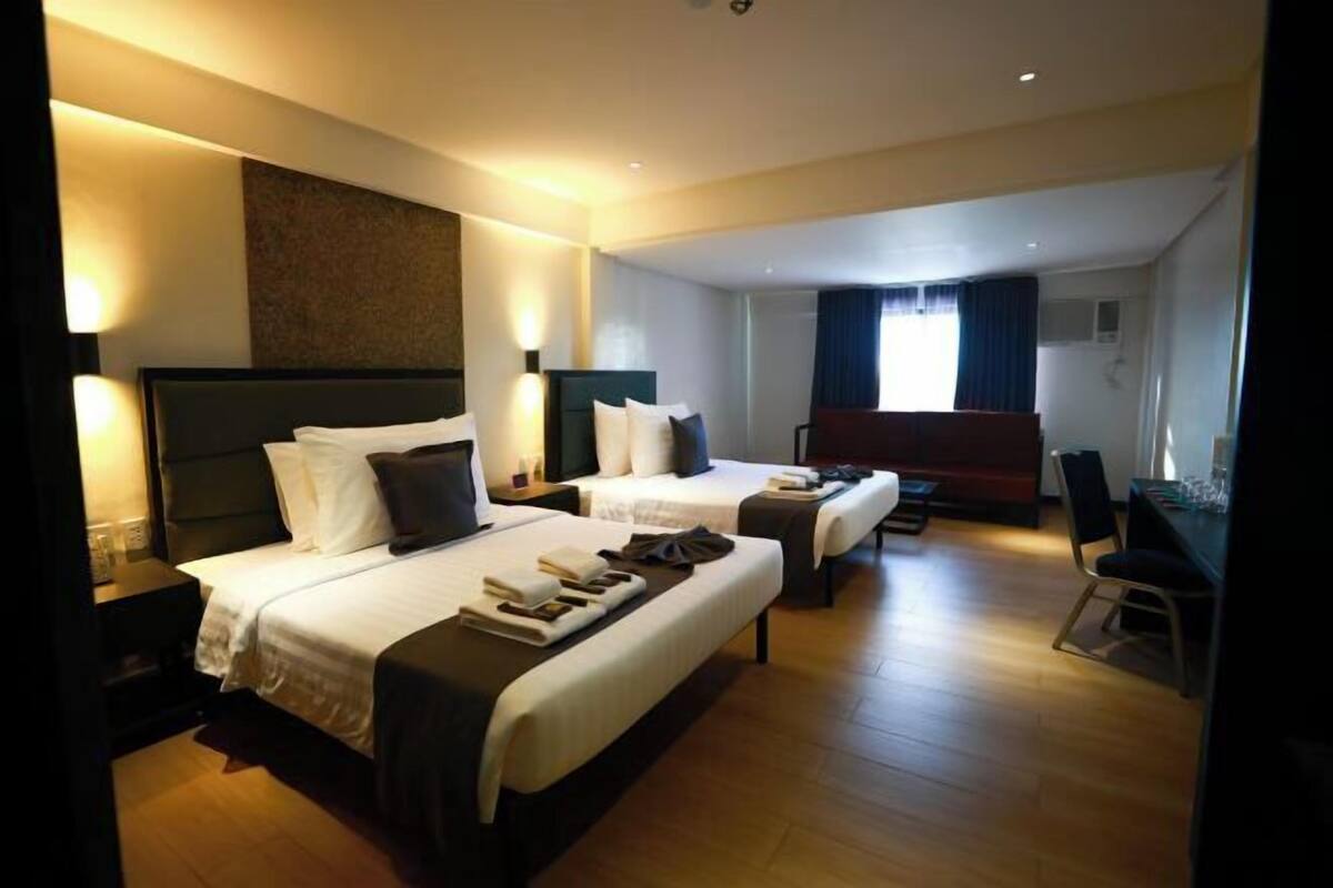 Habitación de hotel con dos camas, un escritorio y una zona de comedor.