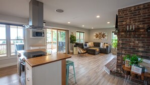 Una cucina moderna con isola centrale, zona pranzo con parete decorata in mattoni e un angolo salotto accogliente con camino.