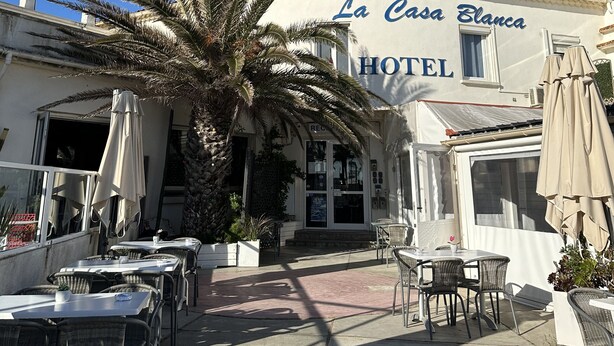 Un área de estar al aire libre con mesas y sillas frente al Hotel La Casa Blanca.