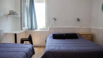 A bedroom with two beds, a desk, and a chair.