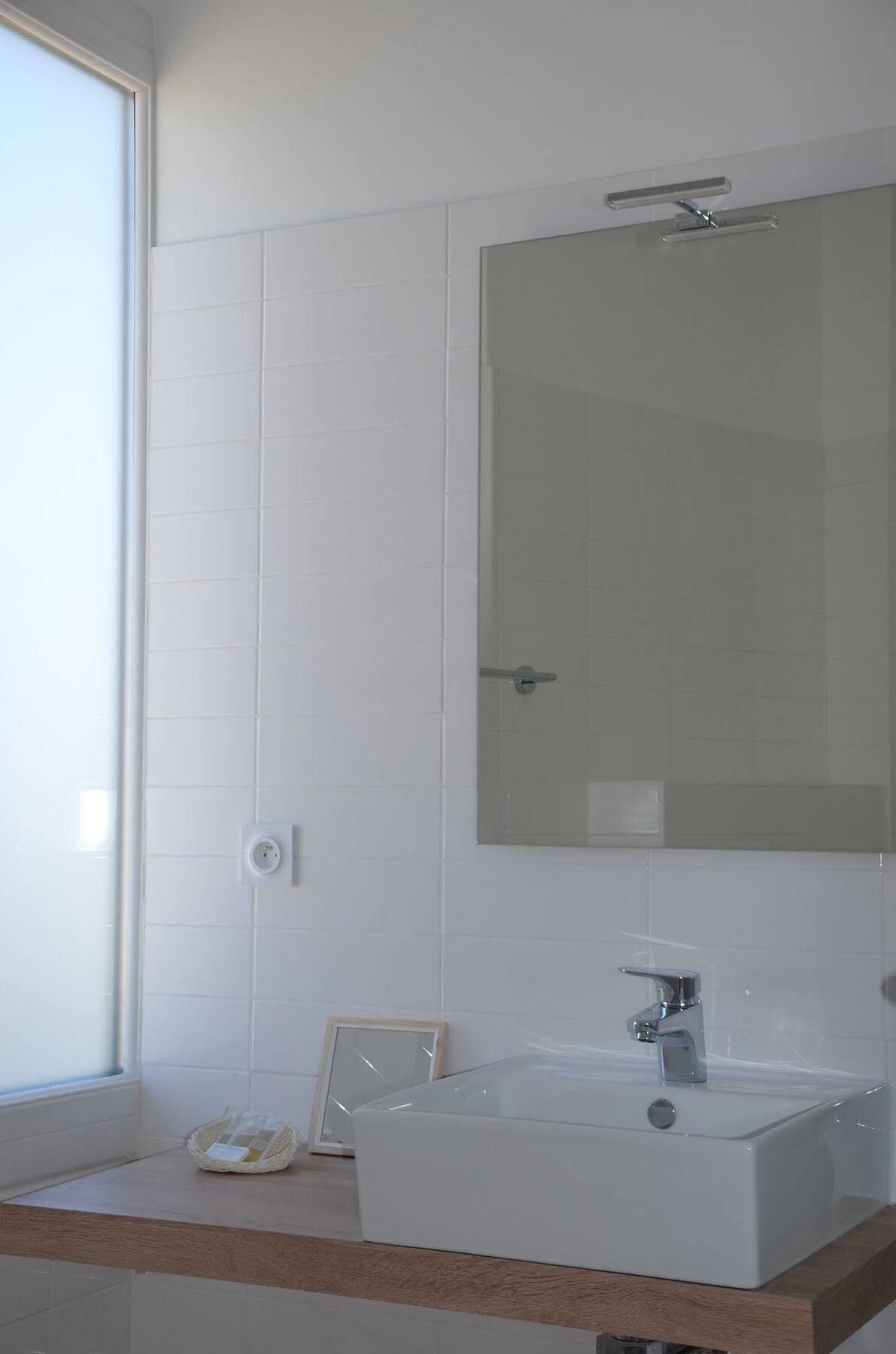 A bathroom with a white sink, a mirror, and a window.