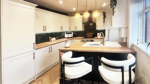 Une cuisine moderne avec des meubles blancs, un plan de travail en bois et une fenêtre offrant une belle vue.