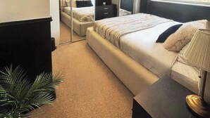 Une chambre à coucher avec un lit, une table de chevet, une lampe et un grand miroir.