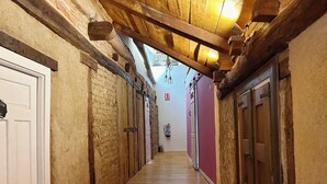 Ein schmaler Korridor mit Holzdielen, Backsteinwänden und Holzbalken an der Decke.