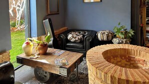 Ein gemütliches Wohnzimmer mit Ledersofa, einem Holztisch und einem Stuhl mit Ziegelmuster.